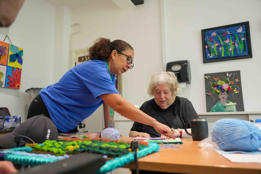 Sarah being supported by Activity Leader Graciela in a Textiles session