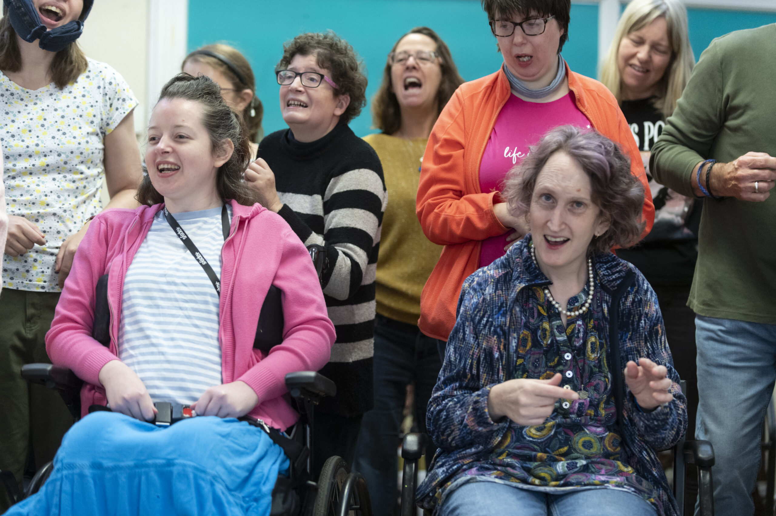 A group of people standing and in wheelchairs sing together at The Meath Epilepsy Charity Skills Centre.