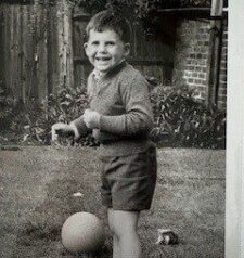 A black and white picture of Michael playing football in the garden as a young boy.
