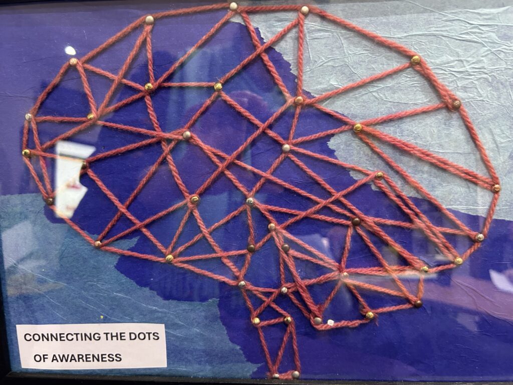 A picture of a human brain created in purple string and mapping pins.