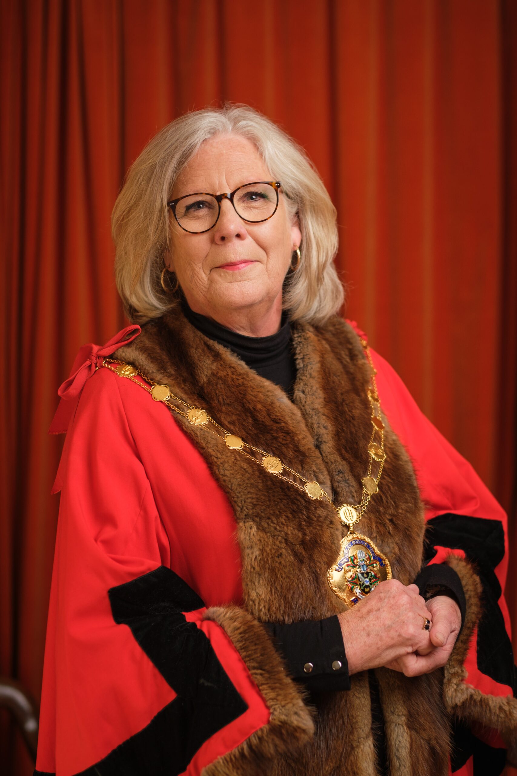 Cllr. Penny Rivers Mayor of Waverley official phot. Penny is smiling wearing a red ceremonial robe and her chains of office.